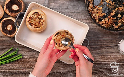 Приготовьте шампиньоны. Измельчите лук и чеснок. Обжарьте чеснок и лук на сковороде 1 минуту. Отрежьте ножки грибов и измельчите их. Шапочки оставьте целыми. Когда лук размягчится, добавьте к нему измельченные ножки грибов. Посолите и поперчите. Обжарьте пару минут. Разогрейте духовку до 180 градусов. Противень застелите пергаментом. В каждую шляпку гриба положите начинку, обжаренную на сковороде. Выложите начиненные шляпки на противень и запеките в духовке 20 минут.