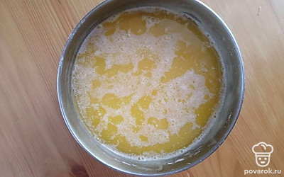 Растопите сливочное масло. Влейте растопленное сливочное масло в тесто. Следите за тем, чтобы масло не было горячим. Тщательно все перемешайте до получения однородности. Выдавите сок из лимонов. Должно получиться примерно 100 мл. Натрите лимонную цедру с одного лимона на мелкой терке.