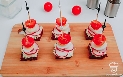 Добавьте в канапе половинку помидора черри и закрепите шпажкой.