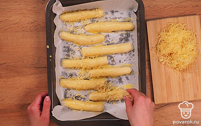 Приготовьте палочки. Сформируйте из теста палочки. Выложите их на противень, застеленный пергаментной бумагой. Оставьте еще немного отдохнуть и приподняться. Через 15 минут яичный желток взбейте с 2 ст.л. молока и смажьте палочки. Сверху посыпьте тертым сыром. Запекайте в духовке, разогретой до 180 ˚C, 15 минут.