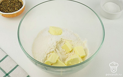 В глубокую миску просейте муку с разрыхлителем, добавьте сахар с солью и куски подмороженного масла. Разомните все содержимое в крошку.