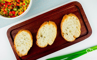 Обжаренный багет смажьте половинками чеснока. После этого пропитайте каждый кусочек хлеба оливковым маслом. Можно использовать силиконовую кисточку для равномерного распределения.