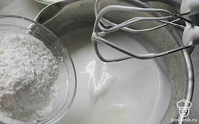 Всыпьте в белки половину сахара и взбейте смесь 1 минуту. Добавьте кукурузный крахмал. 