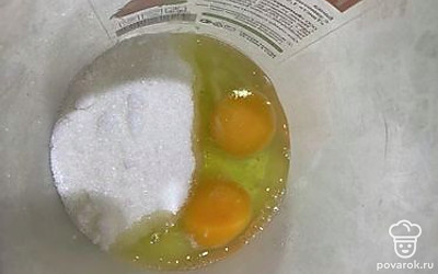 В миску для взбивания к яйцам добавьте сахарный песок.