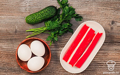 Сварите яйца вкрутую, очистите. Вымойте огурец. Вымойте и измельчите петрушку. Крабовые палочки при необходимости разморозьте, очистите от упаковки. Огурец порежьте на мелкие кубики. Крабовые палочки мелко нарежьте.