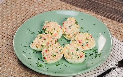 Яйца, фаршированные крабовыми палочками выложите на сервировочное блюдо, сверху посыпьте измельченной петрушкой.