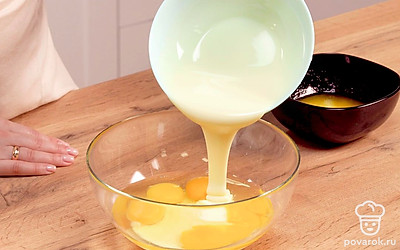 Начните готовить сгущенный бисквит для торта. Для этого смешайте муку с содой. В яйца добавьте сгущенку и растопленное масло.