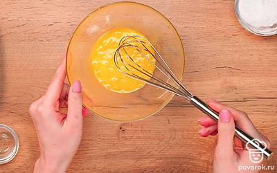 Начните готовить тесто для бананового бисквита. Для этого желтки двух яиц соедините с одним целым яйцом в глубокой миске. Добавьте ванильный сахар и сахарный песок. Взбивайте минут 5 при помощи миксера. Масса должна превратиться в светлую объемную пену, а пузырьки стать маленькими.