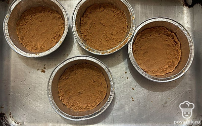 В порционные формы распределите песочное тесто из печенья, слегка его утрамбуйте. 