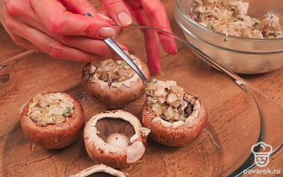 Нафаршируйте грибы. Шляпки шампиньонов выложите на противень, смазанный маслом. Начините грибы приготовленной на сковороде смесью. Сверху посыпьте шампиньоны оставшимся сыром. Запекайте в духовке при температуре 180-200℃ около 25-30 минут.