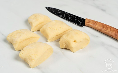 Разогрейте духовку до 200 градусов. Выложите на рабочую поверхность охлажденное тесто. Скатайте из него небольшую колбаску и разделите ее на равные части.