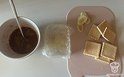 В кипятке разведите какао порошок, форму для пирожного застелите пищевой пленкой, банан нарежьте на пластинки одинаковой толщины. 