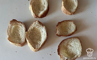 В каждом ломтике хлеба сделайте углубление при помощи столовой ложки, как показано на фото.