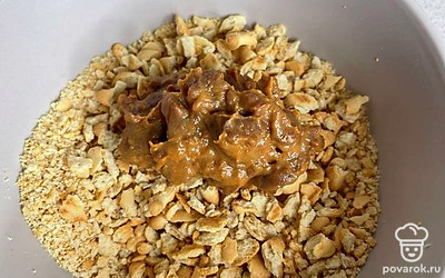 Далее добавляем в измельченные крекеры сливочное масло со сгущенкой. 