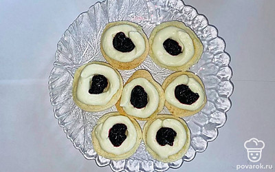 Приготовьте крем. Сливки, из холодильника взбейте с сахарной пудрой. Добавьте творожный сыр и перемешайте, ведите растопленный белый шоколад, смешайте. Выкладывайте немного крема в центр половинки и добавьте джем ежевики.  Первую половинку накройте второй.