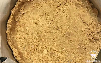 Застелите форму для выпечки пергаментной бумагой и насыпьте две трети печенья, чтобы покрыть все дно. Возьмите стакан и с помощью дна распределите печенье по поверхности. Всыпьте оставшуюся часть печенья и сформируйте бортики вокруг, помогая стаканом сделать их ровными. Уберите форму в морозилку на 20-30 минут.