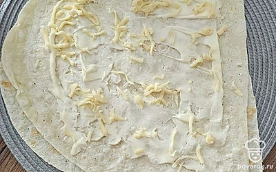 Возьмите лаваш. Смажьте его майонезом. Натрите на терке сыр. 