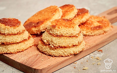 Сформируйте бисквитные ежики. Готовый бисквит освободите от пергамента. Вырежьте четное количество круглых заготовок и сформируйте ежики. Из остатков сделайте посыпку, измельчив их в блендере.