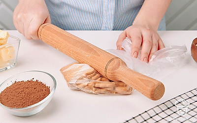 150 грамм печенья положите в целлофановый пакет и раскатайте скалкой до однородной мелкой крошки.