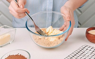 В глубокой миске смешайте печенье с мягким сливочным маслом.