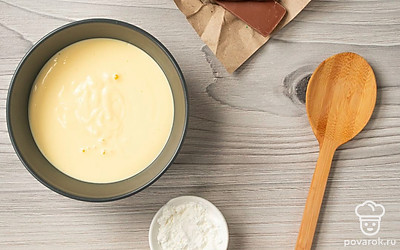 Приступите к приготовлению пломбира. В кастрюлю влейте 4 желтка, добавьте ванильный сахар и 150 г сахарной пудры. Перемешайте венчиком ингредиенты до светлой однородной массы. Влейте молоко, еще раз перемешайте и поставьте кастрюлю на средний огонь. При постоянном перемешивании варите 2-3 минуты, пока масса не загустеет, но не доводите ее до кипения. Затем снимите кастрюлю с огня и остудите.