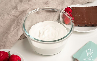 Приступите к приготовлению пломбира. Сливки влейте в миску и взбейте миксером на максимальной скорости до мягких пиков. Влейте сгущенное молоко и снова взбейте. Добавьте рубленый шоколад и клубнику. Аккуратно перемешайте лопаткой массу.