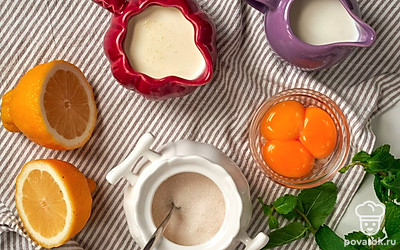 Подготовьте необходимые продукты. Аккуратно снимите с цитрусов цедру, старайтесь не задеть белый слой, иначе десерт будет горчить. Плоды разрежьте на две части, выжмите сок. Процедите лимонный сок и поставьте на время в холодильник. Сливки и яичные желтки поставьте в холодильник. Приготовьте блендер, пластиковый контейнер и креманки. Вымойте и обсушите лимоны и листики мяты для подачи.