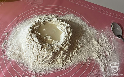 Сделайте лунку в муке, налейте в нее небольшое количество воды. 