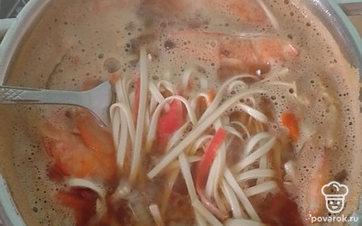 Добавить лапшу, креветки и крабовые палочки. Варить до готовности лапши.