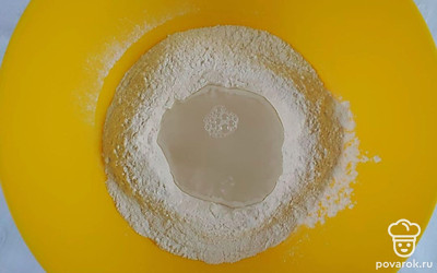 В глубокую емкость просейте муку и сделайте в муке углубление. В стакане с водой растворите соль и вылейте подсоленную воду в муку.