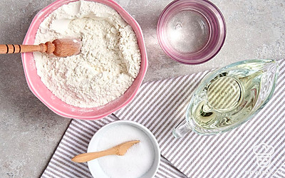 Отмерьте все ингредиенты. Воду предварительно доведите до кипения. Соедините муку и соль, дважды просейте их через сито. Подготовьте скалку, целлофановый пакет, противень и полотенце.