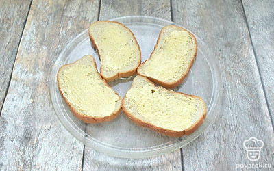 Ломтики батона смажьте майонезом и выложите на тарелку для микроволновки.