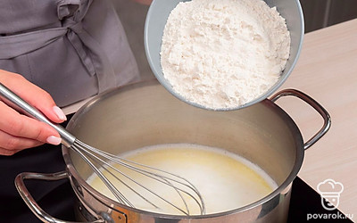 Добавьте муку. Как только масляно-молочная смесь начнет кипеть, убавьте огонь и всыпьте сразу всю просеянную муку. Активными движениями лопаткой тщательно вмешайте муку в жидкость. Тесто должно стать гладким, однородным, отходить от стенок кастрюли. Мешая, прогрейте тесто на медленном огне еще 1-2 минуты, чтобы мука хорошо заварилась. Снимите кастрюлю с плиты и оставьте тесто остывать до теплого состояния.