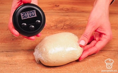 Замесите тесто. Насыпьте в миску муку, добавьте половину масла, воду, посолите. Сначала перемешайте ложкой, потом руками. Оно не должно липнуть к рукам. Переложите тесто на стол и продолжайте месить 5-10 минут, чтобы оно стало мягким, эластичным, гладким. Заверните комок в пищевую пленку или полиэтиленовый пакетик и поместите в тепло на 30 минут.