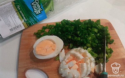 Подготовьте начинку. Для этого мелко нарежьте зеленый лук и 4 вареных яйца. 