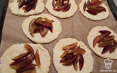 Переложите заготовки из теста на пергамент. В центр выложите сливу. Края оставьте свободными. 