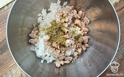 К рису добавьте лук с рыбой, приправу для рыбы и посолите по вкусу. Перемешайте.