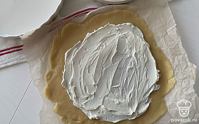 Тесто раскатайте, переложите на пергамент и смажьте творожным сыром.