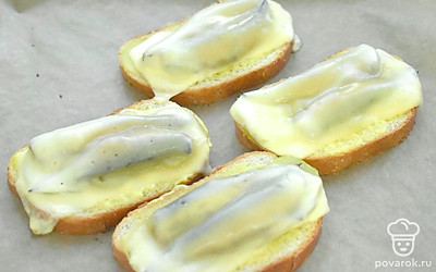 Отправьте противень с заготовками бутербродов в разогретую духовку. Запекайте бутерброды со шпротами 6-8 минут.