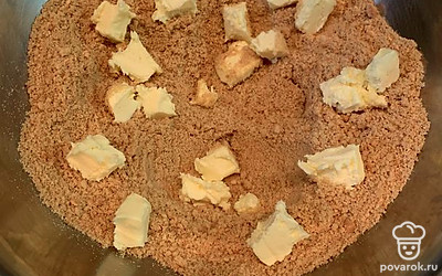 Песочное печенье тщательно измельчите в крошку. Добавьте нарезанное на куски сливочное масло.