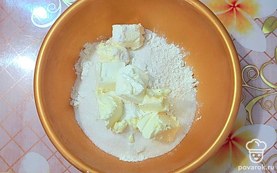 В глубокую посуду просейте муку и разрыхлитель. Добавьте сахар (100 граммов) и нарезанное сливочное масло. Разотрите все руками.