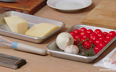 Просейте муку. Очистите лук и чеснок от шелухи. Ополосните и высушите помидоры черри, разрежьте их пополам. Измельчите сыр на средней терке. Подготовьте форму для запекания. Разогрейте духовку до 180° C.