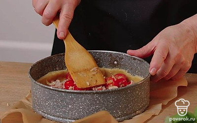 На дно формы с тестом выложите ровным слоем помидоры черри и жареный бекон с луком.