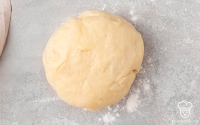 По истечении времени посыпьте стол отложенной мукой, выложите на него поднявшееся тесто. 