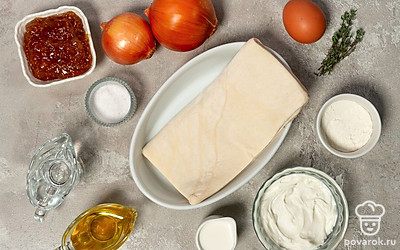 Разморозьте слоеное тесто в соответствии с инструкцией на упаковке. Хорошо охладите сливки. Помойте и почистите лук. Ополосните и обсушите тимьян и яйцо. Приготовьте миску, чашку, миксер, сковороду, скалку. Застелите противень бумагой для выпечки. Включите духовку на 180°С.