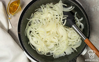 Поставьте сковороду на огонь ниже среднего. Налейте на нее оливковое масло и хорошо разогрейте. Выложите в масло лук и пожарьте его, периодически помешивая, около 5 минут до золотистого цвета.
