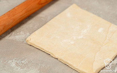 Посыпьте стол мукой, выложите на него слоеное тесто. Раскатайте тесто в пласт толщиной около 4-5 мм.