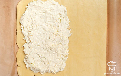 Раскатайте тесто в пласт на листе пергамента. Выложите начинку на одну половину и равномерно распределите по этой половине теста.