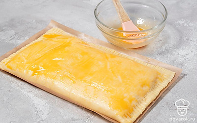 Накройте начинку второй половиной теста и хорошо склейте края. Сверху смажьте пирог желтком.