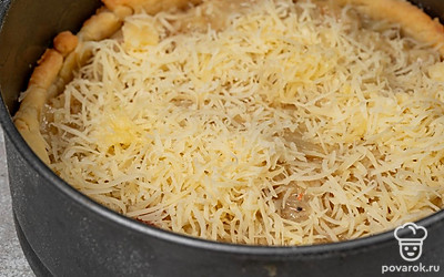 Мелко натрите сыр. Выложите на выпеченную основу из теста лук, равномерно его распределите. Посыпьте лук сыром.